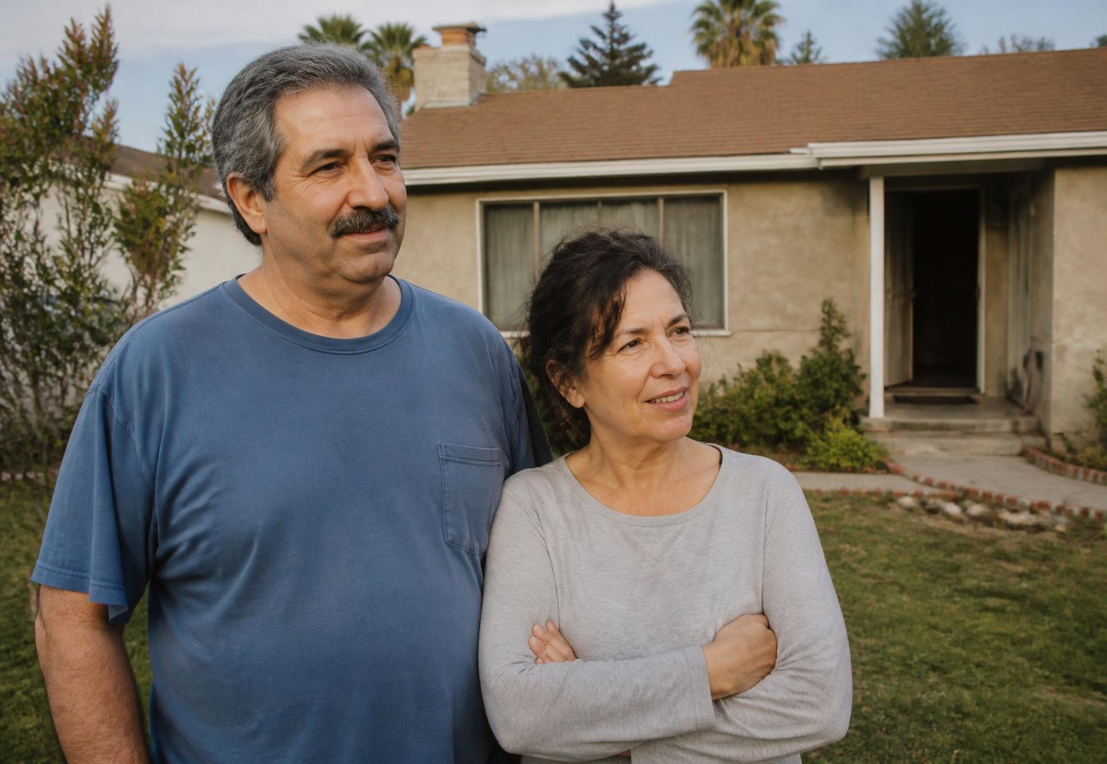 Longtime homeowners standing outside their older Southern California house